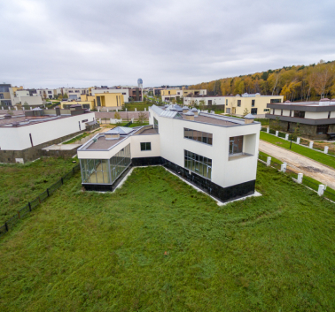 A picturesque house featuring a green roof, set against a vibrant green lawn, embodying tranquility and natural beauty.